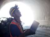 Construction worker with a laptop standing inside a tunnel