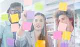Two men and a woman brainstorming and putting up post-it stickers in different colors on to a glass wall. Levasil colloidal silica are used to improve performance of pressure sensitive adhesives (PSA).  