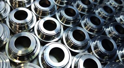 Shiny silver color stainless steel parts background. Regular industrial metal production pattern. Nouryon offers aqueous cleaning chemical products for all metals such as steel, aluminum, brass, aerospace metals, and many others.