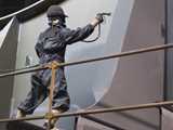 worker with full protection suite spay-painting large metalic structure