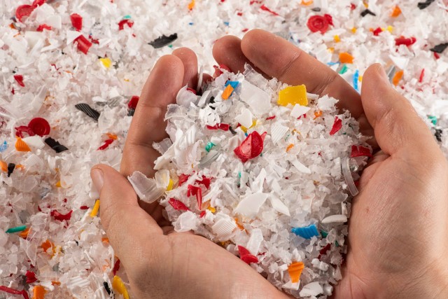 Two hands holding small pieces of plastic waste