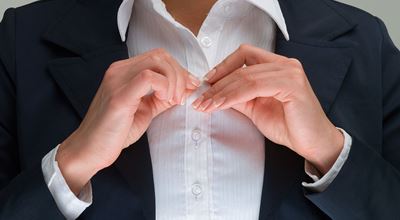 A woman fastening the last buttons on her blouse