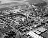 Aerial view of a large industrial complex with factories, warehouses, and a canal surrounded by farmlands.