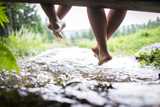Stock photo of woman's feet dangling near a water stream surrounded by greenery